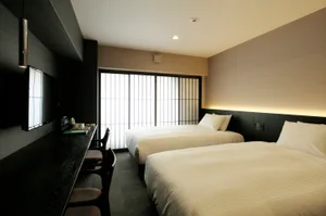 Modern minimalist hotel room with a textured fabric bedspread and a television mounted on the wall.