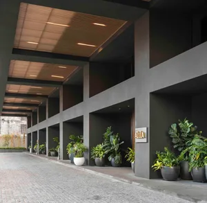 Modern lobby entrance with green plants in planters, concrete pillars, and a sleek design.