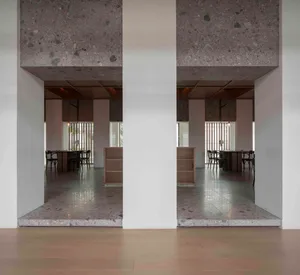 Modern restaurant interior with concrete floors and walls, featuring tables and chairs.