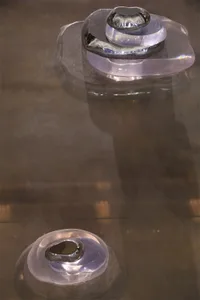 A modern art display featuring glass sculptures installed on a glass surface.