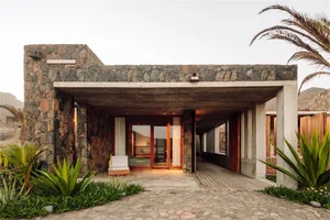 A modern residential house featuring a stone and concrete exterior.