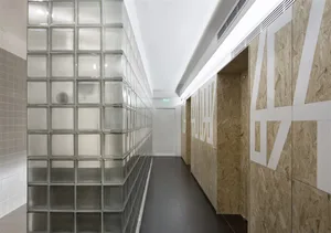 Modern office corridor featuring glass block walls and wooden OSB partitions.