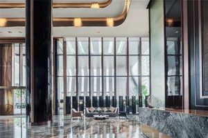 A modern lobby features glass walls and sofas with cushions.