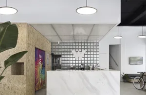 Modern office reception area with marble counter, OSB paneling, and glass block wall