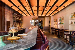 Modern restaurant interior with a concrete bar counter and high-top seating.