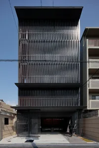 Modern tall building with metal cladding and large vertical windows on a sunny day with a clear blue sky.