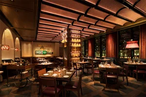 Well-lit restaurant interior featuring wood and copper accents, with tables set for dining and a bicycle as a decorative elem