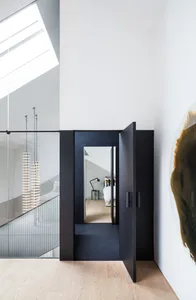 A modern bedroom featuring a black glass door and a large glass window, with a minimalist interior design.