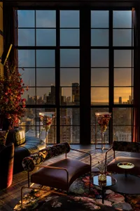 Modern living room with a glass window overlooking a cityscape during sunset.
