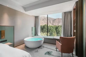 Modern, minimalist bedroom featuring concrete flooring, glass window, and furniture.