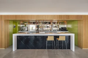 Modern bar with black marble counter, timber shelves, and vibrant green accents.