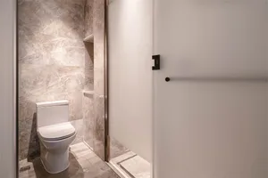 A modern bathroom with marble walls and white toilet.