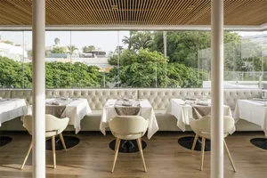 Table setting in a modern restaurant with white leather banquettes and white tablecloths.