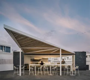 Rooftop bar with wooden roof structure, metal frames, and high seating.