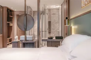 Modern bedroom with minimalist design, white bedding, and integrated bathroom.