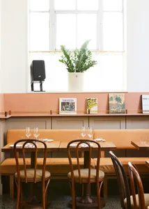 Interior design of a cafe featuring mid-century modern furniture with wooden tables and chairs, brown leather seating, and de