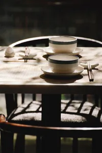 A set of ceramic dinnerware on a table with place mats and chopsticks.