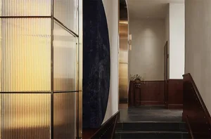 A hotel corridor featuring illuminated metal panels and dark stone stairs.