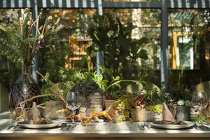 A dining table setting in an industrial-style interior with wood, glass, and metal elements.