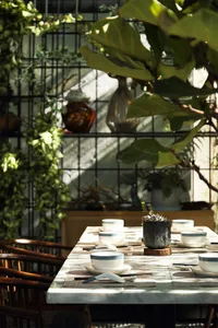 A modern dining room setup featuring ceramic tableware and greenery.
