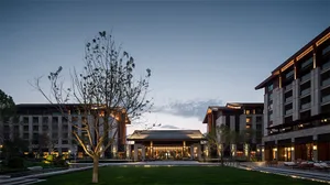 An illuminated entrance to a modern hotel exterior during dusk, featuring contemporary architectural design with warm lightin