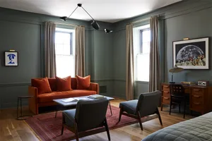 Living room with a modern interior design, featuring a red sofa with matching cushions and a wooden floor with a red rug.
