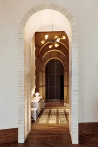 Arched entrance with marble pillars and a wooden hallway with geometric flooring.