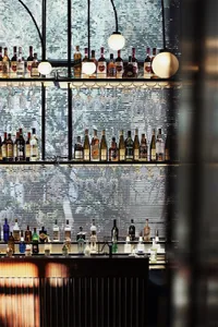 A modern bar interior displaying an assortment of alcohol bottles and hanging glasses.