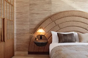 Modern bedroom interior with a fabric-covered bed and wooden elements.