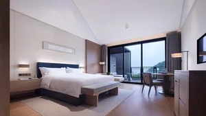 Modern bedroom with wooden accents and a large window overlooking nature.