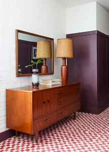 Modern bedroom featuring wooden furniture, patterned flooring, and decorative lamps and flowers.