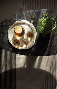 A modern coffee table setting with a glass teapot and cups, placed on a black stone surface.
