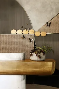 A sleek and stylish entryway with a gold leather bench, metal accents, and a potted plant.