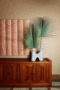 A stylish modern interior design featuring a wooden cabinet with ceramic vase and plant.