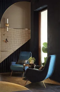 Modern lobby with two blue upholstered armchairs and a small round side table with a plant on it, positioned near a large win