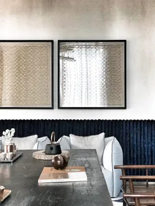 A modern minimalist dining area featuring a sleek, textured concrete table surrounded by blue upholstered chairs.