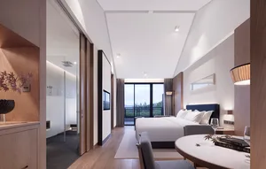 Modern hotel bedroom featuring a wooden floor, a double bed with white bedding, a round table with books and a glass, and a g