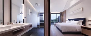 Modern minimalist bedroom featuring a white bed with white linens, a blue headboard, and a glass shower door.