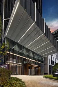 現代酒店入口採用玻璃面板與鋁合金結構，搭配照明燈光，在晴朗的日子呈現明亮外觀。