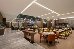 明亮的現代酒店早餐區，搭配木質地板與玻璃天花板。
