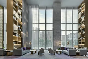 Modern hotel lobby featuring large glass windows overlooking a cityscape