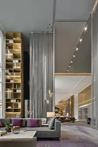 Modern lounge area with contemporary furniture, high ceilings, and large windows.