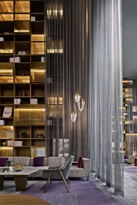 Interior view of a modern lobby featuring wooden furniture, glass walls, and fabric curtains.