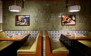 Restaurant interior with green tile walls and wooden tables with white tablecloths