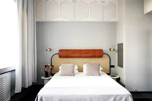 A minimalist bedroom featuring a bed with a leather headboard and white bedding.