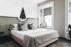 Modern minimalist bedroom with concrete walls, fabric bedding, and wooden accents.