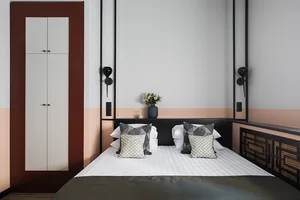 A minimalist bedroom featuring a white bed with geometric-patterned pillows.