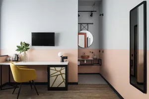 A modern, minimalist workstation featuring a sleek desk, a yellow chair, and a flat-screen TV.