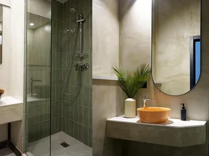Modern bathroom with concrete tiles and a glass-enclosed shower with a green and tan color scheme.