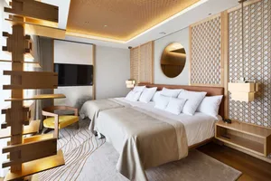 Modern hotel room with a wooden lattice accent wall, white bedding, and a large window allowing natural light to flood in.